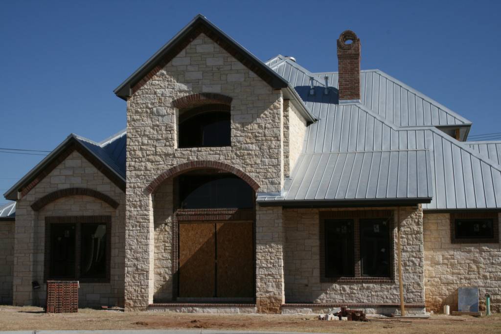 new home with metal roof and rock construction