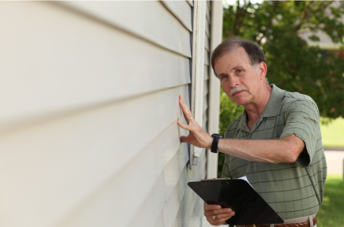 Man inspecting siding on a house